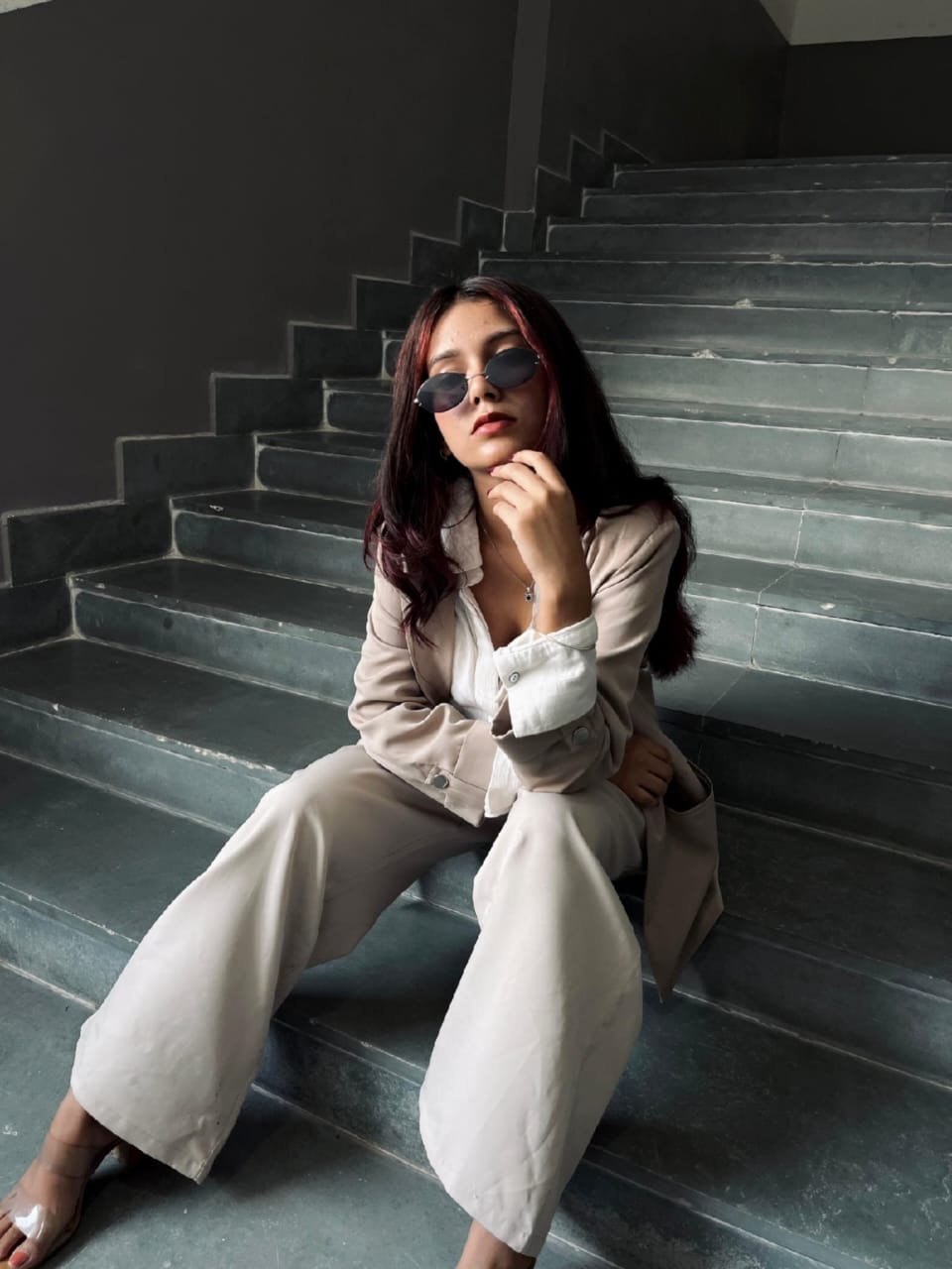 Janvi Saxena in a beige outfit seated on concrete stairs